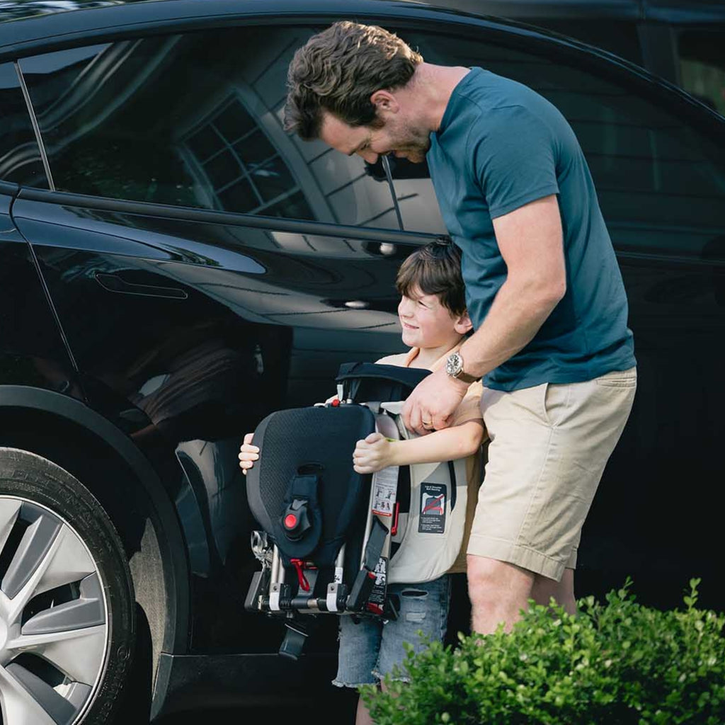 Father helping a son with a folded car seat